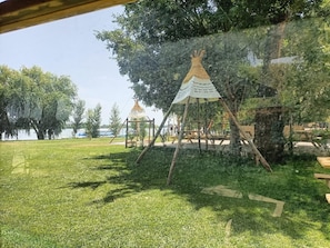 Une zone herbeuse avec une structure en bois et un bâtiment blanc en forme de tente, sur lequel on peut lire du texte.