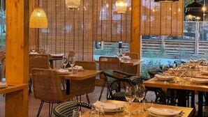Un restaurant avec des poutres en bois, des chaises en osier et des tables dressées pour le repas.