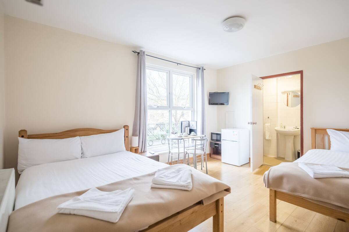 Une chambre d’hôtel avec deux lits, un bureau, une télévision et une salle de bain.