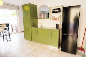 Compact kitchen with microwave, refrigerator, and dining area through the doorway.