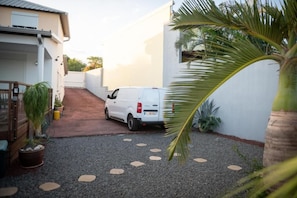driveway leads to a home with a garage and lush greenery.
