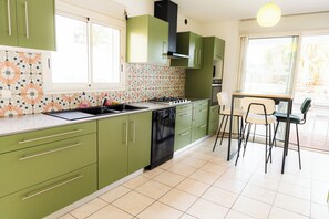 Kitchen features a stove, sink, and dishwasher, adjacent to a dining area with a table and chairs.