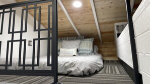 A bedroom with a wooden ceiling, a bed with white bedding, and a black metal partition. - The Birds Nest in Central Phoenix (Phoenix)