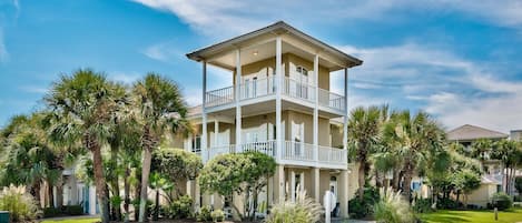 A multi-story building with balconies, surrounded by palm trees and well-maintained lawns.