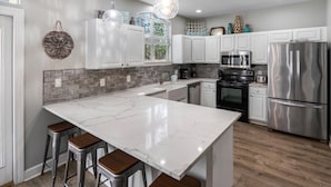 A modern kitchen with white cabinets, a marble island, stainless steel appliances, and a hanging light fixture. - Latitude Adjustment | Luxury Beach Retreat ☀️ | 15% Off July Weeks (Miramar Beach)