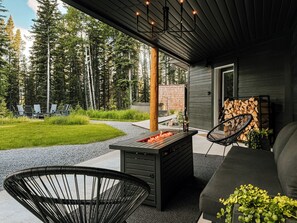 Eine Außenpatio mit Feuerstelle, Sitzgelegenheiten und Blick auf einen Wald.