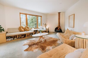 Ein gemütliches Wohnzimmer mit einer Couch, einem runden Couchtisch, einem Kamin und einem großen Fenster.
