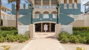 A large, two-story building with a central entrance, surrounded by white fences and palm trees. - Cinnamon Beach Sunrise: Unit 853 (Palm Coast)