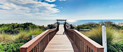 A wooden boardwalk leading to a gazebo by the sea.