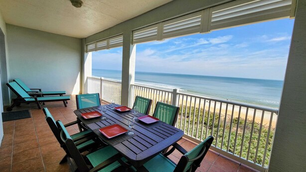 A covered patio with a table set for two, overlooking a beach. - Cinnamon Beach Sunrise: Unit 853 (Palm Coast)