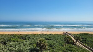 A beach with a wooden boardwalk and dense vegetation in the foreground. - Cinnamon Beach Sunrise: Unit 853 (Palm Coast)