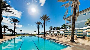 A swimming pool with clear blue water, surrounded by palm trees and lounge chairs. - Cinnamon Beach Sunrise: Unit 853 (Palm Coast)