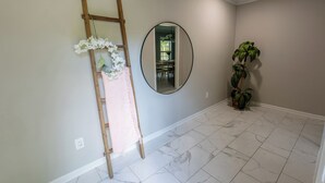 A hallway with a wooden ladder, a round mirror, and a potted plant. - Private Pool–Renovated Home for Groups/Getaways (Memphis)