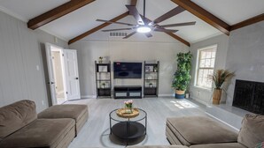 A living room with a ceiling fan, a fireplace, and a television. - Private Pool–Renovated Home for Groups/Getaways (Memphis)