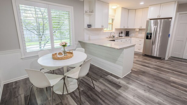 A modern kitchen with white cabinetry, a stainless steel refrigerator, and a dining area with a round table and chairs. - Private Pool–Renovated Home for Groups/Getaways (Memphis)