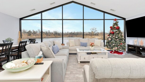 Un salon moderne avec une grande fenêtre, un sapin de Noël et un coin repas.