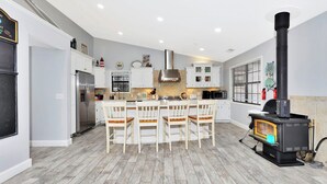 Une cuisine moderne dotée d’un îlot central, de meubles blancs, d’une cuisinière intégrée et d’une grande fenêtre.