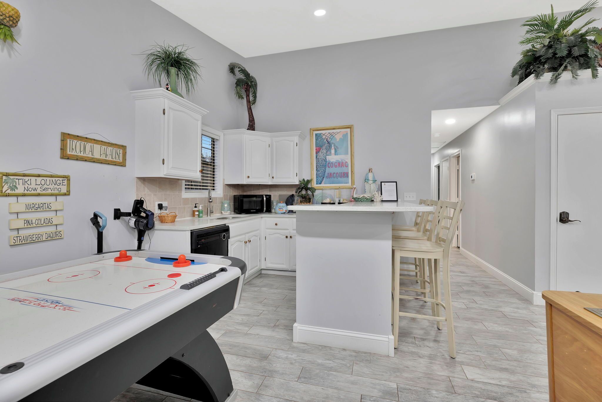 A modern kitchen with white cabinets, a central island, and a foosball table.