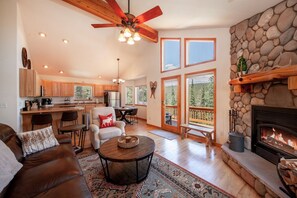 A spacious living room with a fireplace, a dining area, and a kitchen.