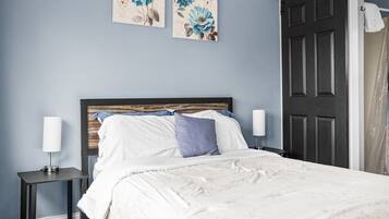 A bedroom with a bed, two nightstands, a headboard, and two wall-mounted floral artworks.