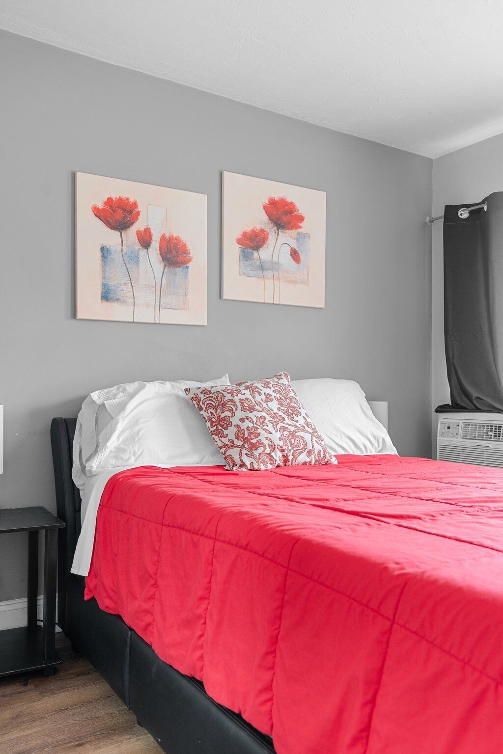 Un dormitorio con una cama, una mesita de noche y dos cuadros colgados en la pared.