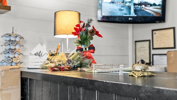 A reception desk with a lamp, a sign, and a decorative plant. - Washington Park Motel (Norwell)