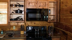 Une cuisine compacte dotée de meubles en bois, d’un four à micro-ondes, d’un four traditionnel et d’une machine à café.