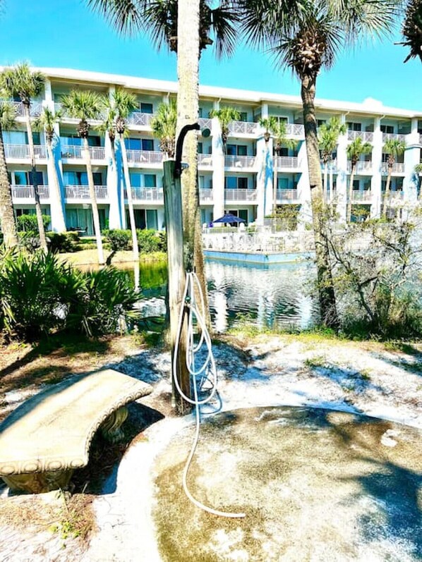 A hotel with a pool area, surrounded by palm trees and a water feature.