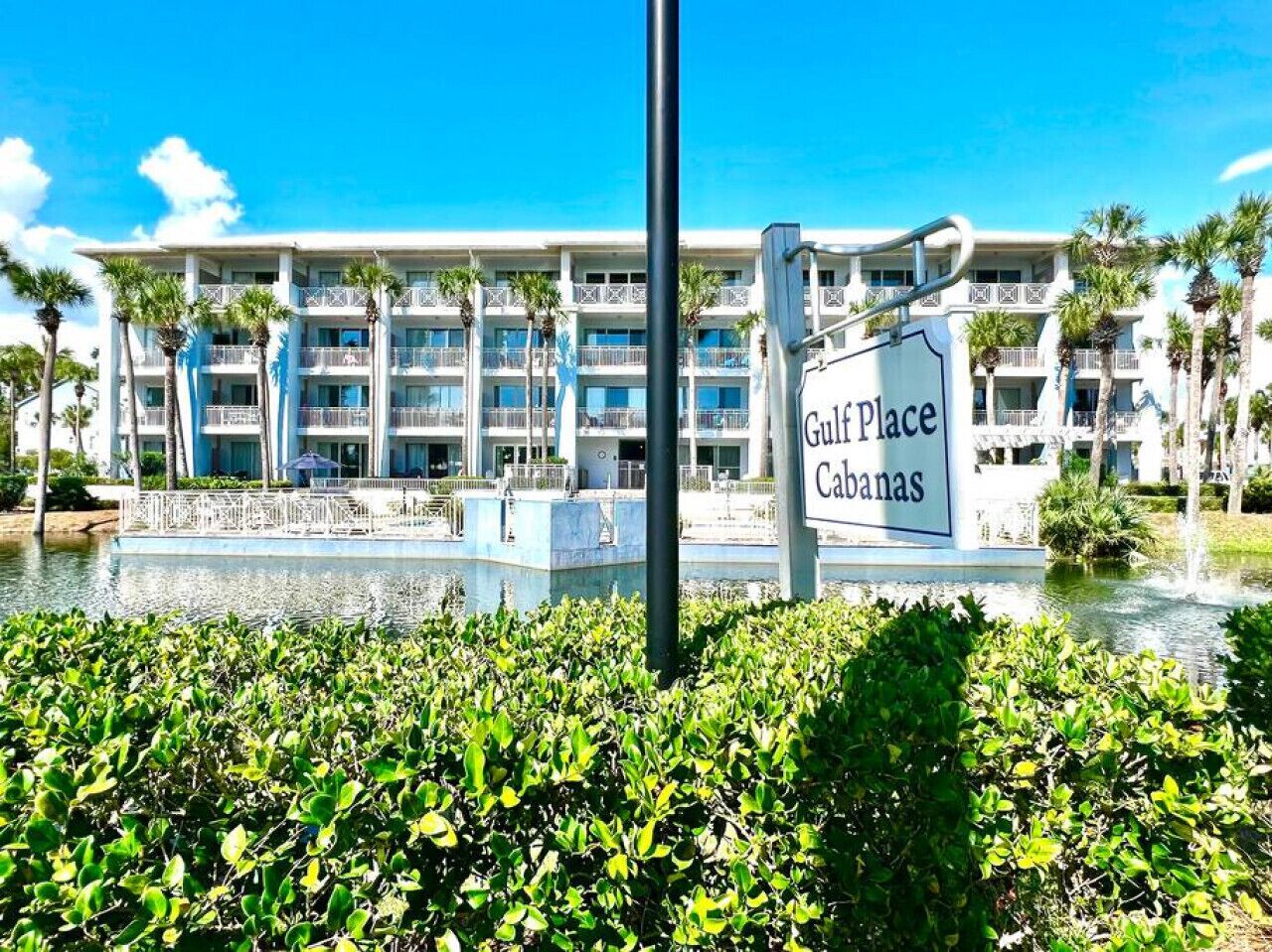 A hotel named Gulf Place Cabanas with a pool and palm trees in the foreground.