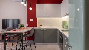Una cocina moderna con una pared de acento roja, un comedor con mesa y sillas, y un horno empotrado.
