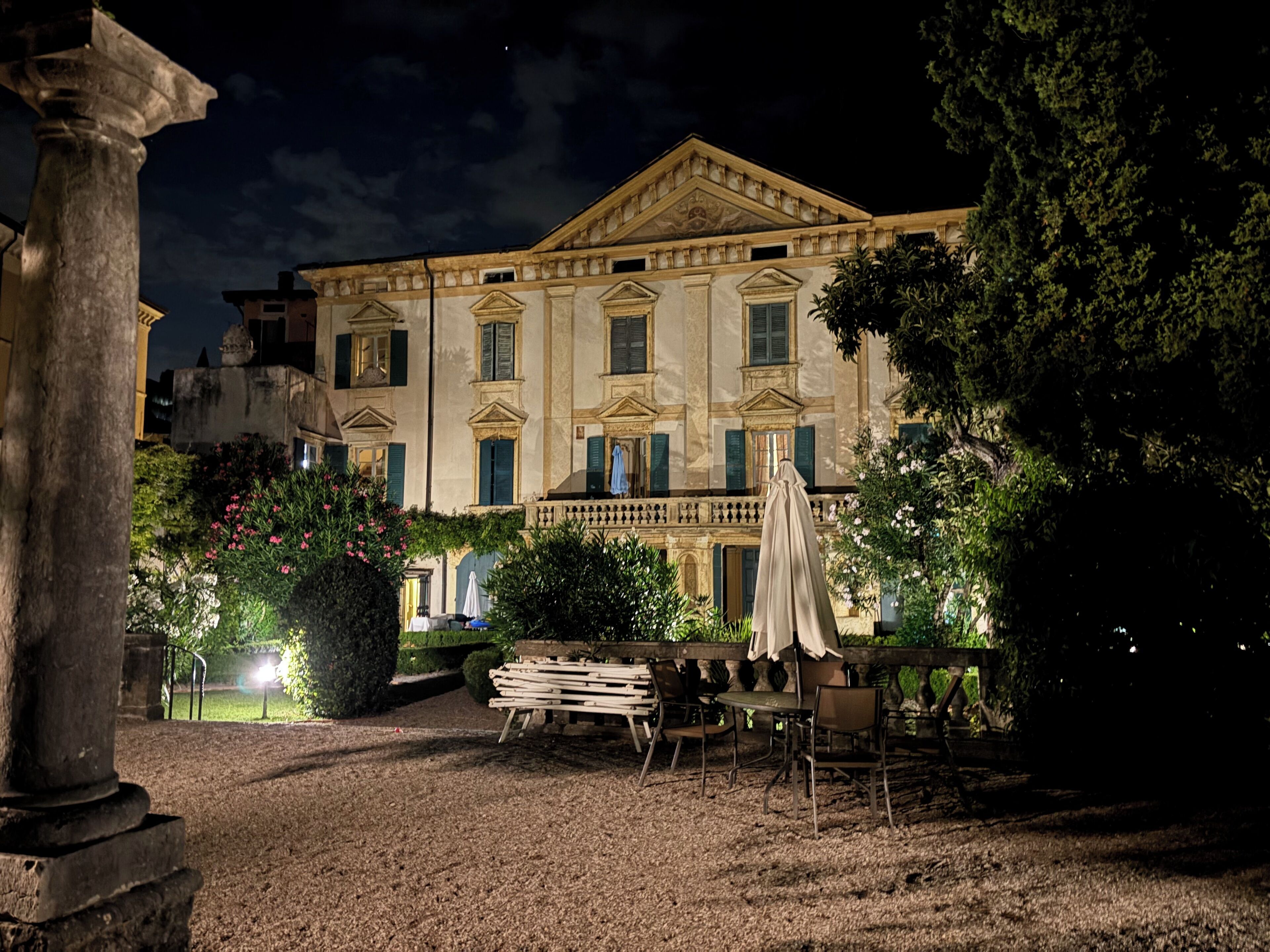 Ein historisches Gebäude mit klassischer Architektur, ein Innenhof mit Außenbestuhlung und ein gepflegter Garten.