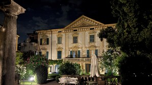 A historic building with classical architecture, a courtyard with outdoor seating, and a well-maintained garden.