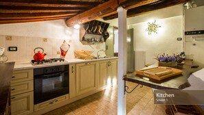 A kitchen with wooden beams, a stove, and a sink.