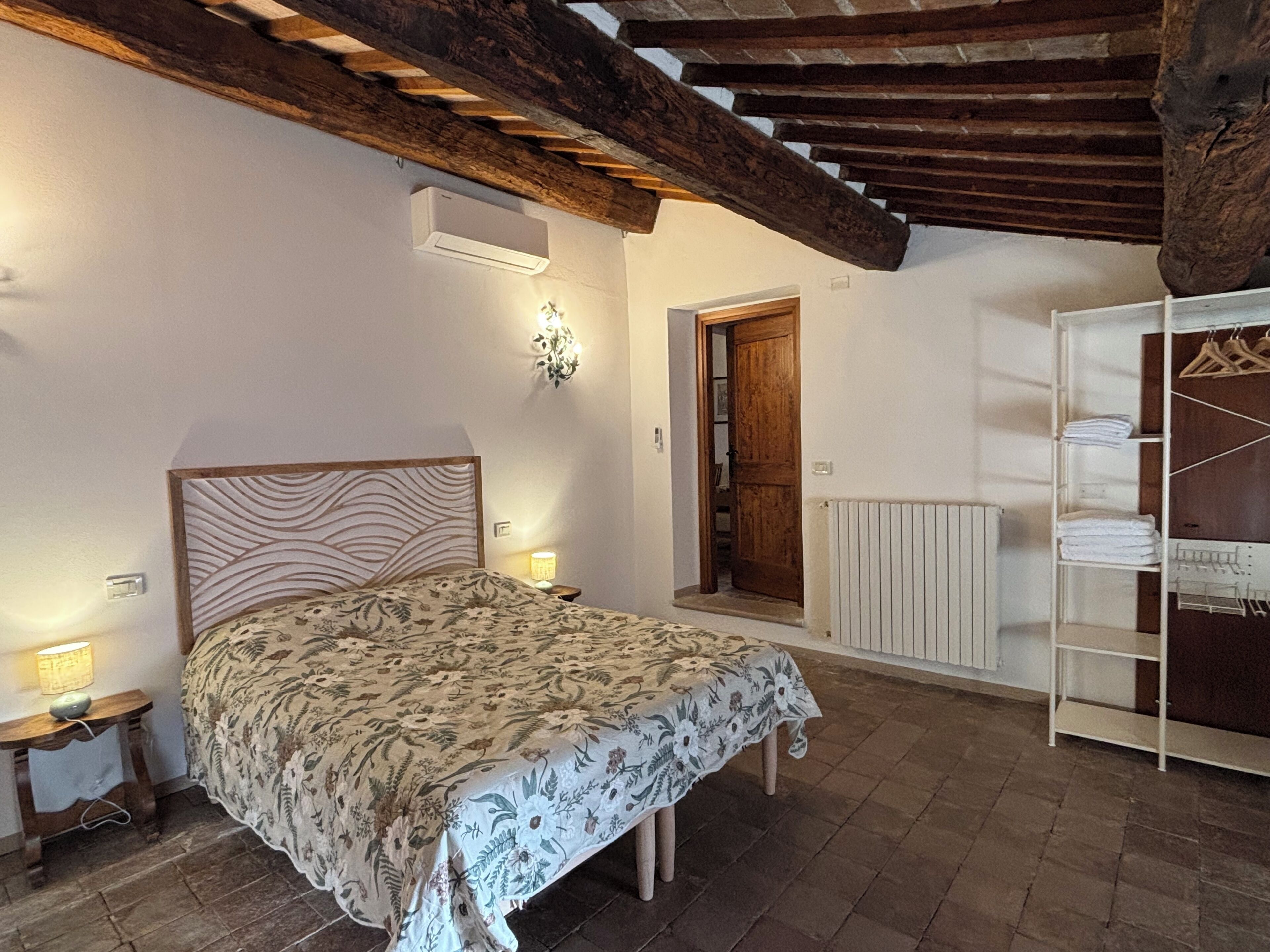 Une chambre à coucher avec un lit en bois, une table de chevet avec une lampe, un radiateur et une armoire en bois.