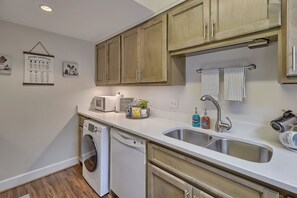 Kitchen features a dishwasher, stainless steel sink, and a small refrigerator.