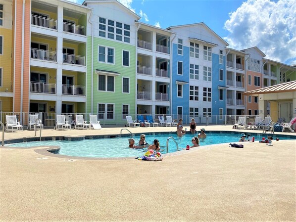 A multi-story hotel with a swimming pool, outdoor seating, and balconies. - The Sanctuary at False Cape - Back Bay View (Virginia Beach)