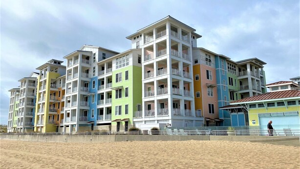 Un hotel de varios pisos con balcones, situado cerca de una playa de arena.