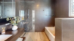 A modern bathroom with a glass shower enclosure, a bathtub, and a vanity with a sink and a vase of flowers. - Beautiful Gem In The Heart of Condado - 3 mins from the beach! (San Juan)