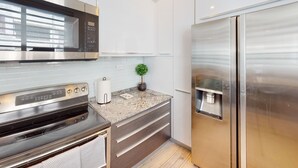 A modern kitchen with a stainless steel refrigerator, a built-in microwave, and a granite countertop. - Beautiful Gem In The Heart of Condado - 3 mins from the beach! (San Juan)