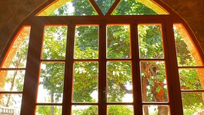 A large arched window with multiple panes, each offering a view of lush greenery. - Ultimate experience of living in a traditional Legacy with a natural setting (Sidon)