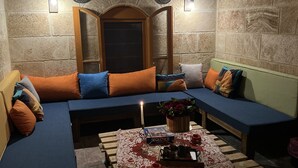 A cozy seating area with a wooden bench and cushioned sofas, a table with a candle, and a decorative plant. - Ultimate experience of living in a traditional Legacy with a natural setting (Sidon)