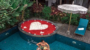 A man relaxing in a swimming pool with a heart-shaped flower bed, surrounded by lush greenery and a lounge chair. - LONG TERM Rent Only - Budget Friendly Private Room (Ubud)