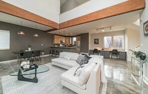 Relax in this stylish living area with a high ceiling, sofa, and dining space.