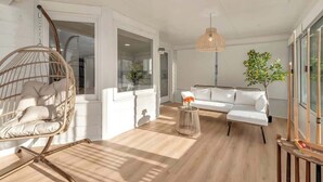 A spacious living room with a hanging chair, a white sofa, and a small round table with a vase of flowers. - Pool House/ 9beds/4Ba/ Kings/ Billiard/ Air Hockey (Lawrenceville)