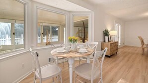 A dining area with a round table, white chairs, and a wooden cabinet. - Pool House/ 9beds/4Ba/ Kings/ Billiard/ Air Hockey (Lawrenceville)