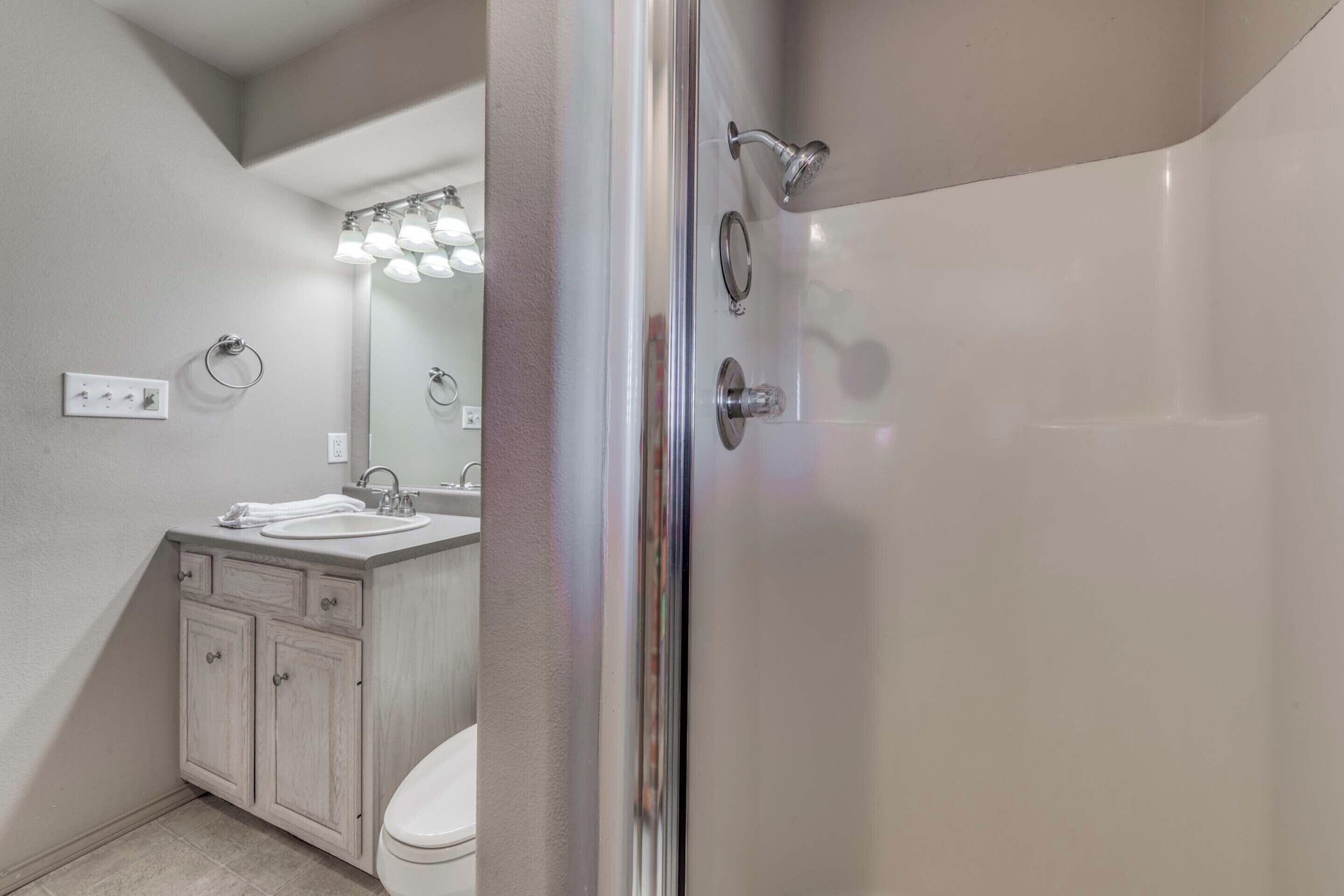 Un baño moderno con ducha, inodoro y tocador.