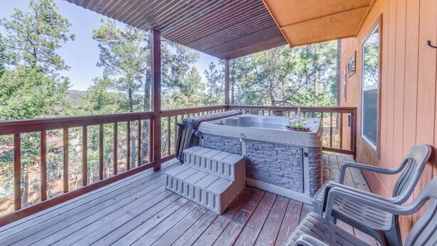 Terraza exterior cubierta con jacuzzi, escalones de madera y sillas de plástico.
