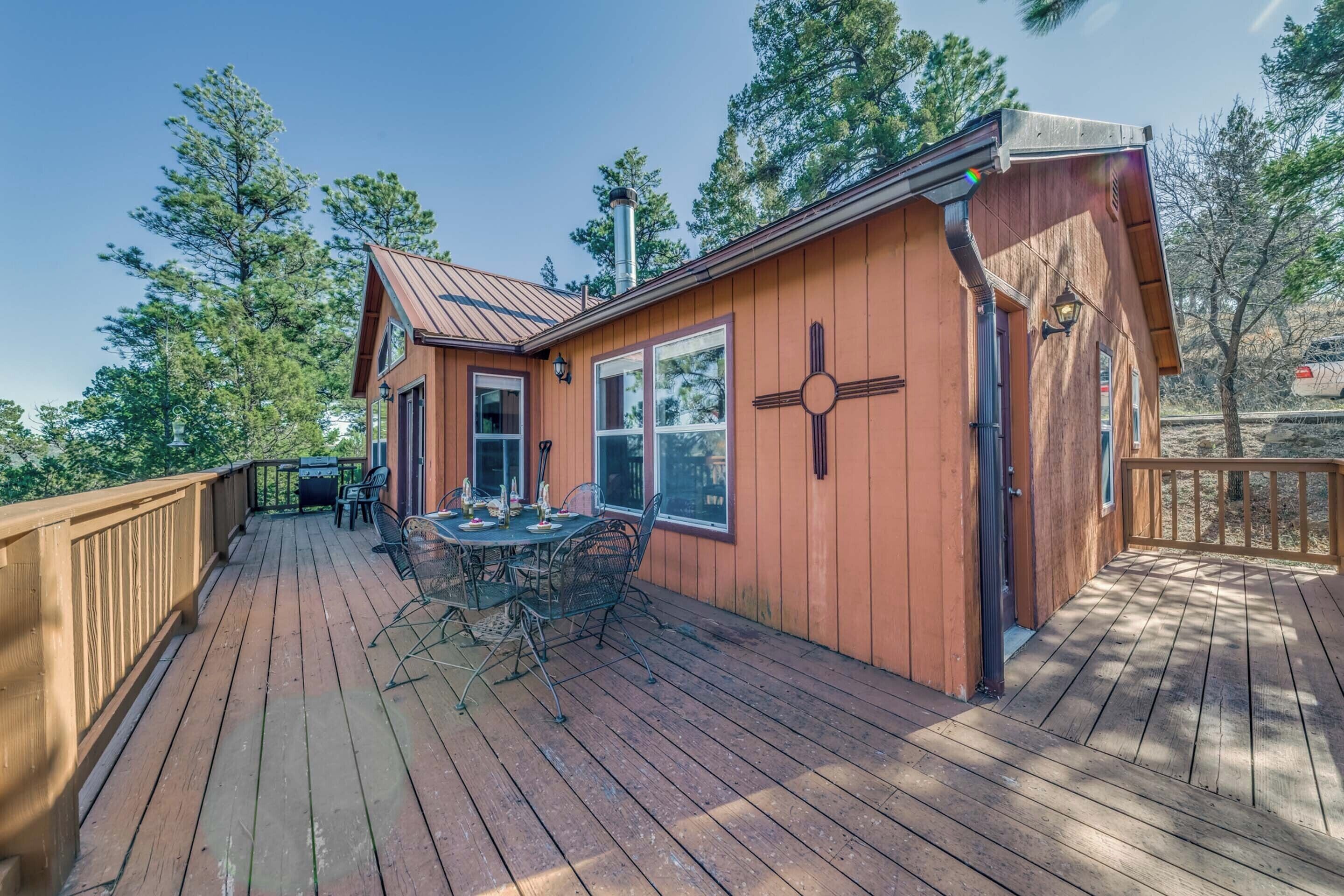 A wooden deck with a dining table and chairs, surrounded by a wooden railing.