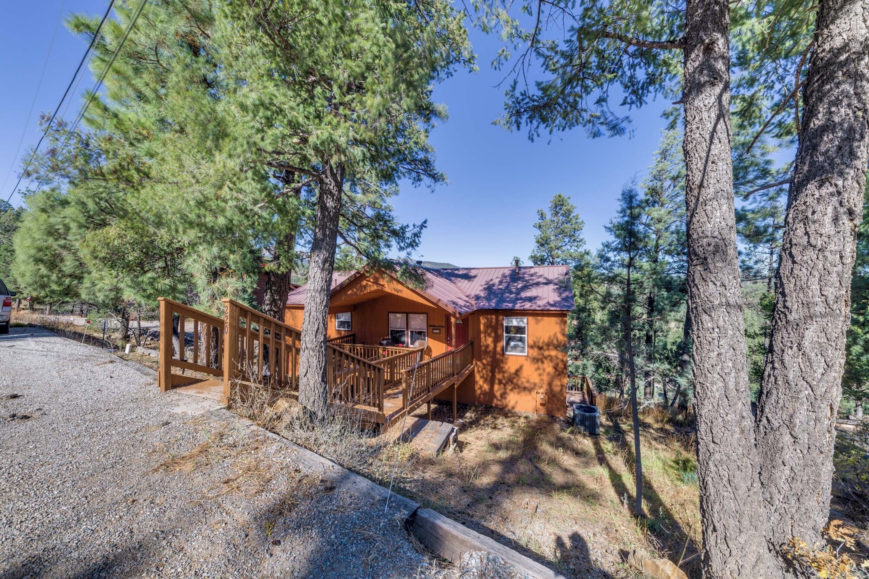 A cabin with a wooden deck and a metal staircase leading to the entrance.