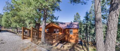 A cabin with a wooden deck and a metal staircase leading to the entrance.